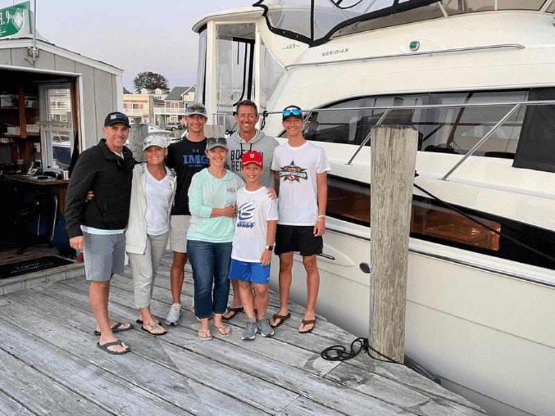 Family in front of their yacht docked at a marina.