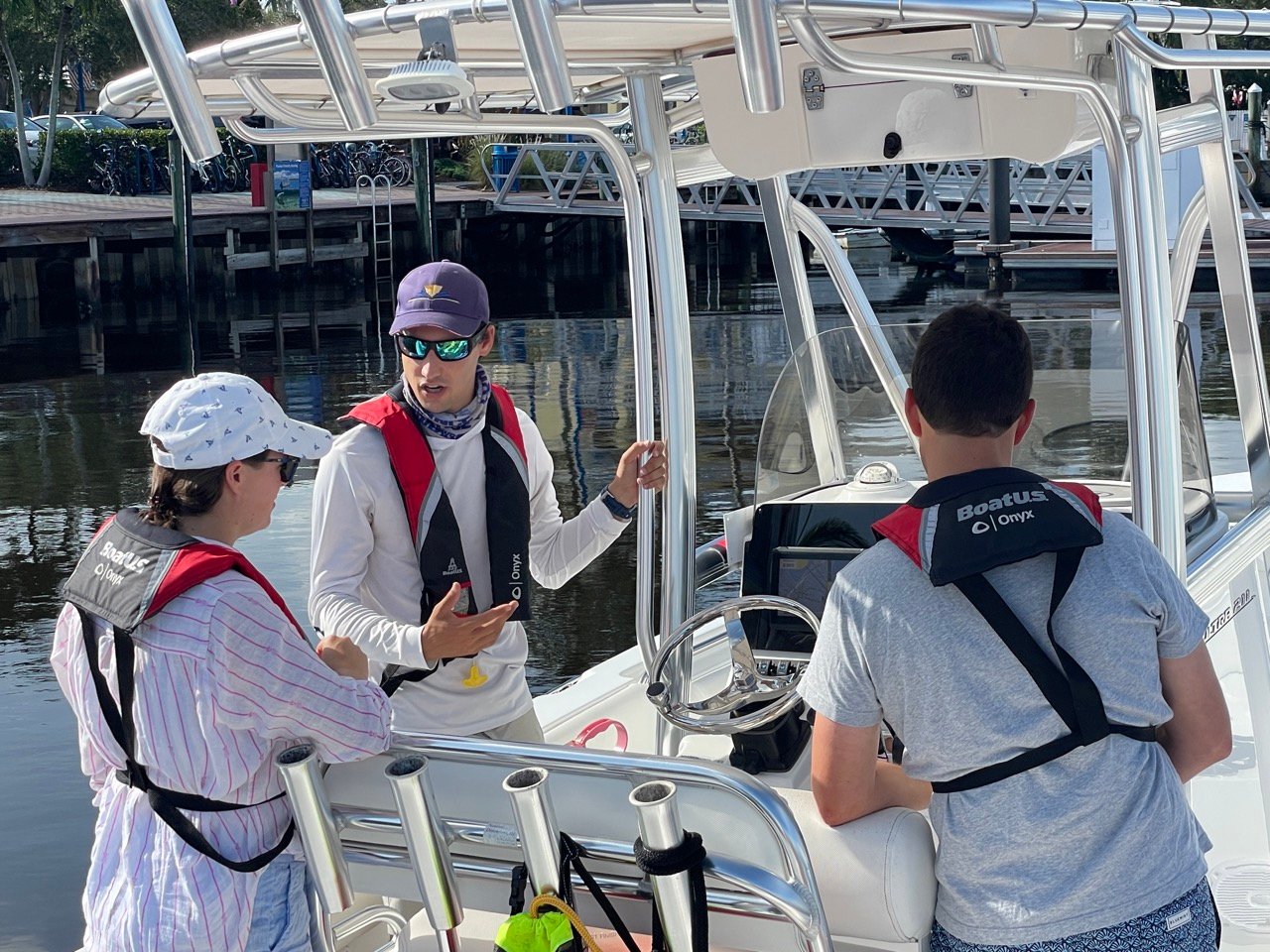 Female instructor giving lessons on boat to two young men in life jackets