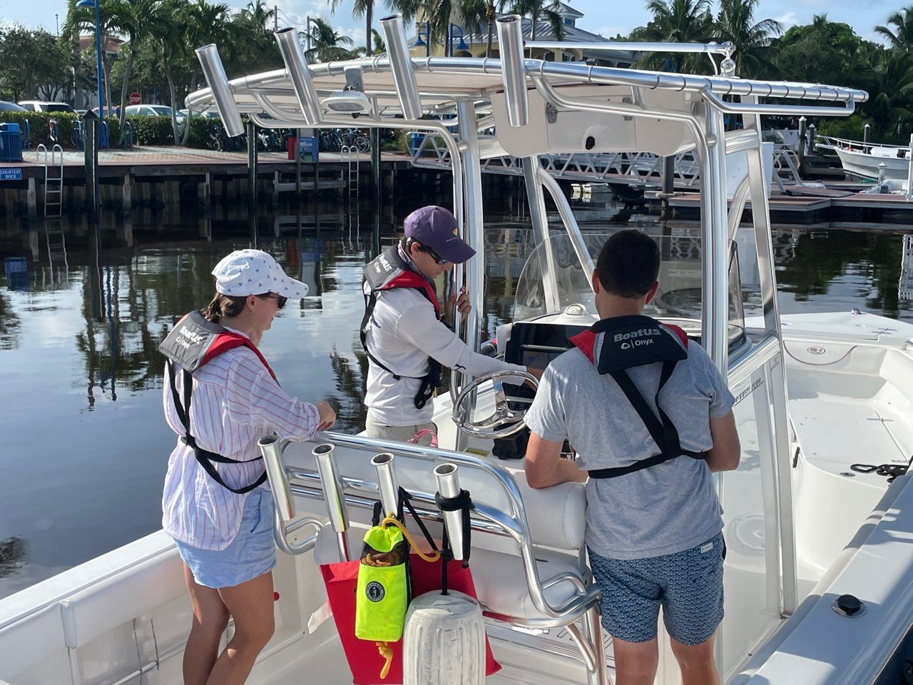 Female instructor giving lessons on boat to two young men in life jackets