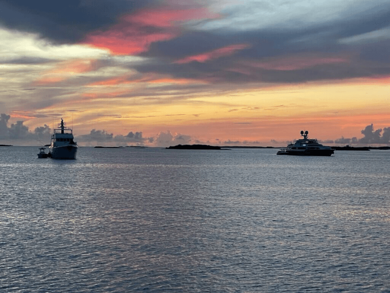 Sunset on the water with view of two yachts.